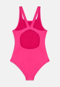 Maillot de bain une pièce rose vif avec des bretelles épaisses formant un dos en V et un grand découpage circulaire dans la zone du milieu du dos.