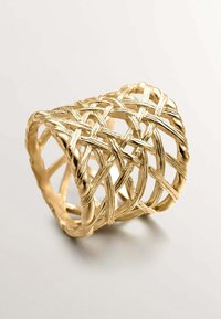 Anillo tejido en tono dorado con un diseño abierto, que presenta hilos entrelazados y una superficie texturizada, creando un patrón de celosía.