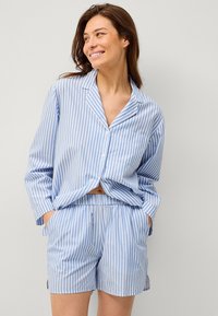 Lysblå og hvid stribet bomulds pyjamas sæt, der har en skjorte med knapper og lomme samt shorts med elastisk talje, afslappet pasform.
