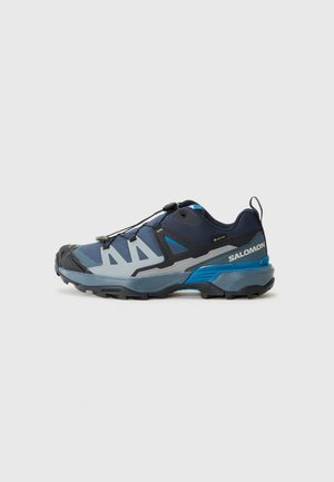 Trail running shoes in navy and light blue with a textured sole, reinforced toe cap, and quick-lacing system; features breathable mesh upper.