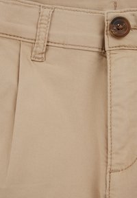 Bežīgas kokvilnas bikses ar krokām, ar vienu brūnu pogu un augšējo šuvumu. Gluda tekstūra un standarta jostas detaļas.