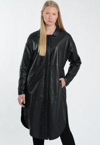 Sort læderjakke med krave, lange ærmer og sidelommer. Har en strømlinet silhuet og mat overflade.