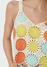 Top de ganchillo con motivos circulares en naranja, amarillo, verde y azul. Hecho de una tela suave con escote en V y tirantes anchos. Detalle texturizado en toda la prenda.