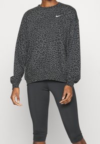 Sudadera negra de cuello redondo con un diseño de estampado de leopardo, que presenta mangas largas y un logo de Nike blanco en el pecho.