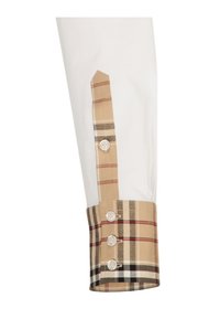 Manica di camicia in cotone bianco con un polsino a quadri beige, caratterizzata da bottoni e motivi contrastanti, inclusi sottili righe rosse e verdi.