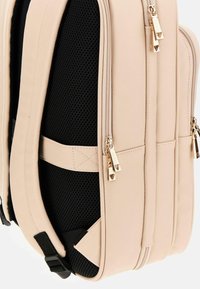 Zaino beige con tessuto testurizzato, pannelli laterali in rete, doppi scomparti con zip e zip in tonalità oro.