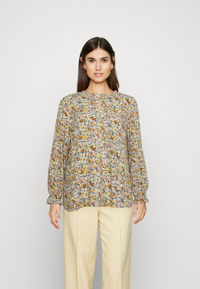 Blusa floral de manga longa com decote redondo e um pequeno detalhe em forma de buraco de chave, apresentando uma mistura de flores amarelas, cor-de-rosa e castanhas sobre um fundo claro.