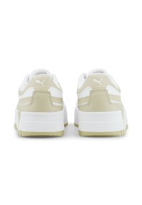 Scarpe sportive bianche e beige dal design pulito, con pannelli laterali testurizzati e una robusta suola bianca. Presentano il logo Puma sul tallone.