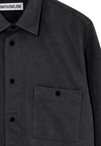 Sötétszürke gombos ing, textúrált anyagból, gallérral, fekete gombokkal és egyetlen melletti zsebből áll. A márkacímke látható.