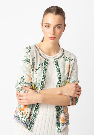 Knit cardigan in light cream, featuring colorful floral patterns in green, orange, and blue. Round neckline with decorative trim and buttons.
