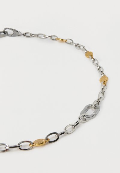 Ασημένιο κολιέ αλυσίδα με κρίκους σε διάφορα σχήματα και μικρές χρυσές οβάλ λεπτομέρειες τοποθετημένες ομοιόμορφα κατά μήκος της αλυσίδας σε λευκό φόντο.