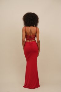 Red two-piece outfit featuring a fitted skirt and a backless top with crisscross straps, smooth texture, and body-hugging silhouette.