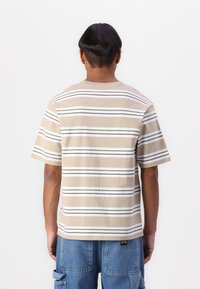 Beige striped t-shirt featuring horizontal lines in white and green, made of cotton, with a round neck and short sleeves.