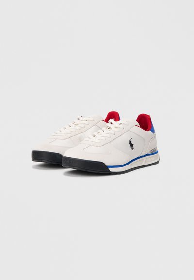 Ténis deportivos brancos com detalhes em vermelho e azul, tecido texturizado, biqueira redonda, sola plana de borracha e logótipo bordado na lateral.