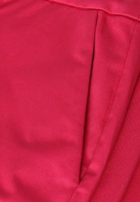 Tissu satin dans une teinte rouge vive, présentant une texture lisse et un subtil éclat, avec des détails plissés et des accents de couture.