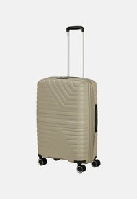 Valigia rigida con un motivo geometrico beige, dotata di manico retrattile, quattro ruote piroettanti e chiusura con zip.