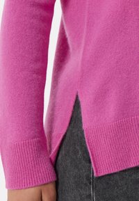 Maglione fucsia con polsini a coste, tessuto strutturato e spacco laterale. Presenta un materiale morbido e leggero per un fit confortevole.