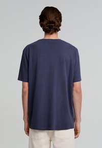 Marineblauwe katoenen t-shirt met een relaxed fit, korte mouwen en een ronde hals. Glad textuur en minimale naden aan de achterkant.