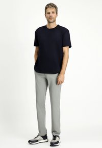 T-shirt a girocollo blu navy, pantaloni slim-fit grigi e sneakers grigio-neri. Tessuto morbido, design semplice e colori a contrasto.