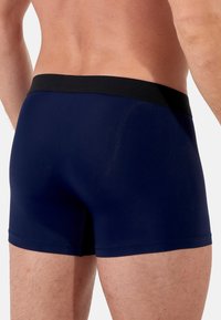 Boxer briefs blu navy con una cintura elastica nera. Il materiale sembra liscio con un design aderente e dettagli di cucitura minimi.