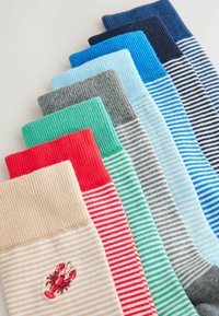 Sept paires de chaussettes rayées de différentes couleurs, une paire beige avec un petit homard rouge brodé à la cheville.
