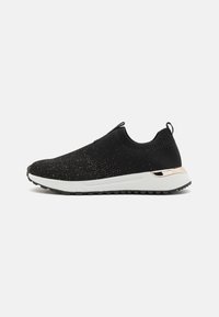 Black knit slip-on sneaker with a textured upper, white rubber sole, and a gold accent on the heel. Features a pull tab for easy wear.