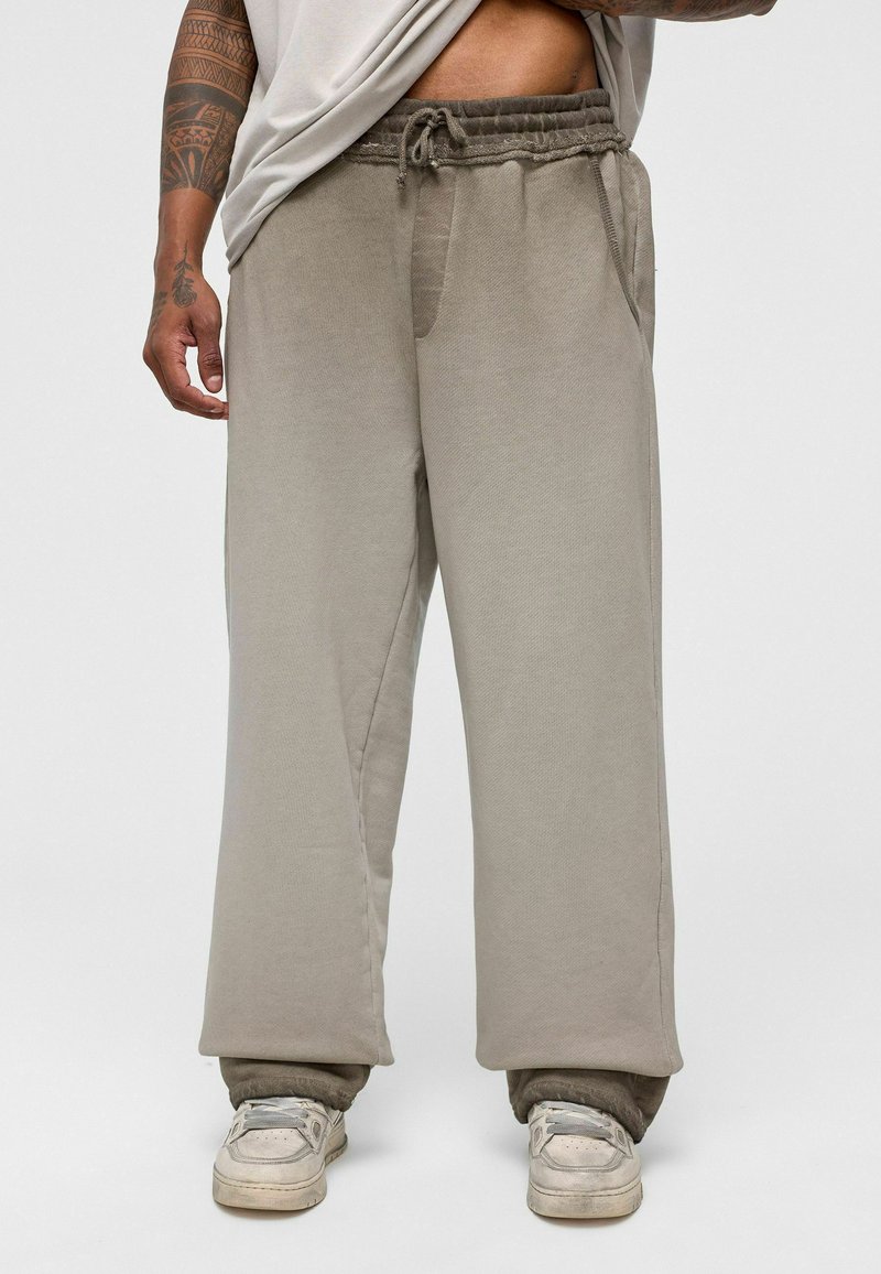 Lichtgrijze sweatpants met een trekkoord in de taille, zijzakken en een losse pasvorm. Gemaakt van zacht, gestructureerd materiaal met een taps toelopende enkellengte.
