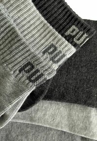 Drei Paare von grau und schwarz gestreiften Socken mit dem Text "RUN" auf den Bündchen, übereinander auf einem weißen Hintergrund angeordnet.