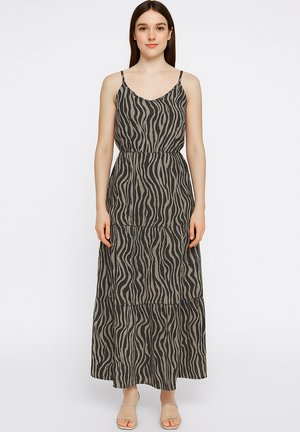 Maxi dress in black with a wavy cream pattern. Features thin adjustable straps, a fitted waist, and tiered skirt design. Lightweight fabric.