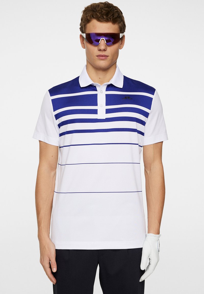Vit polo med blå horisontella ränder, korta ärmar och krage. Strukturerad tyg med en liten svart logotyp på bröstet.