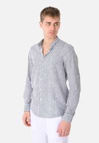 Camicia button-up a righe in lino grigio e bianco. Presenta un colletto con punta, maniche lunghe e polsini a righe a contrasto.