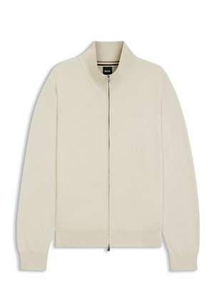 Suéter beige claro con cremallera, cuello alto, puños y dobladillo acanalados, hecho de tela suave. Presenta una marca sutil en el pecho.