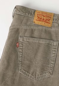 Πίσω τσέπη από γκρι καμβά Levi's τζιν με κόκκινη ετικέτα και δερμάτινο λογότυπο Levi Strauss & Co. στη μέση.