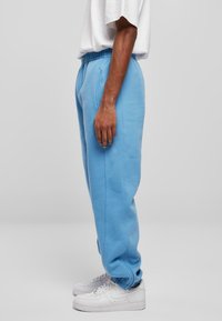 Lichtblauwe sweatpants van een katoenmix met een elastische tailleband, gebundelde enkels en twee zijzakken, gecombineerd met witte sneakers.