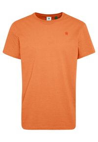 Camiseta naranja de manga corta hecha de algodón, con un cuello redondo y un pequeño logo en el lado izquierdo del pecho, textura suave, diseño casual.