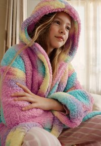 Robe à capuche duveteuse aux couleurs dégradées pastel (rose, bleu, jaune) avec une texture douce, dotée de larges manches et d'une coupe confortable.