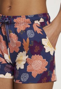 Korte broek met bloemenprint, voorzien van een marineblauwe achtergrond met perzikkleurige, witte en paarse bloemen. Inclusief een verstelbare trekkoord en zijzakken.