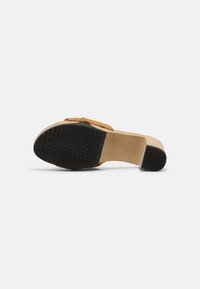 Houten platform sandaal met een zwarte rubberen zool, voorzien van een tan lederen bovenkant en decoratieve banddetails.