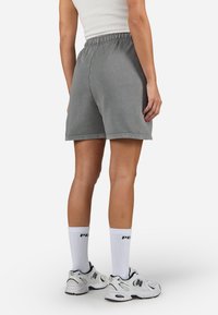 Grey cotton shorts with an elastic waistband, featuring a relaxed fit and visible stitching details, paired with white socks and sneakers.