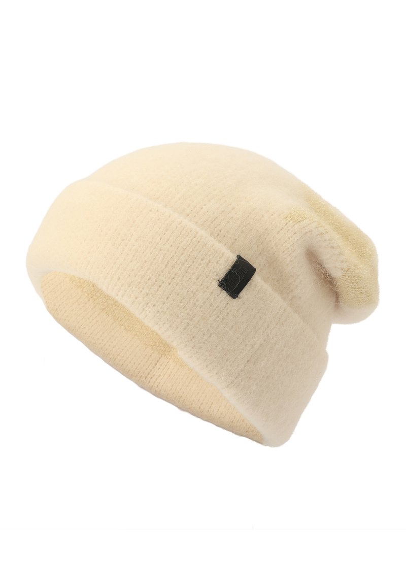Cream knitted beanie with a soft texture, featuring a turned-up cuff and a small black label. The design is simple and slouchy.