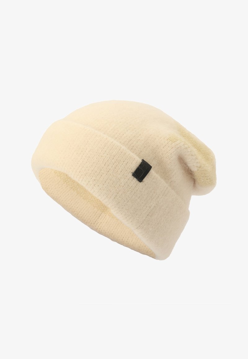 Cream knitted beanie with a soft texture, featuring a turned-up cuff and a small black label. The design is simple and slouchy.
