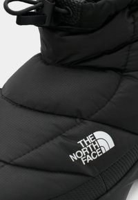 Klimatizacija juodų žieminių batų su „The North Face“ logotipu ir reguliuojama juosta viršuje.