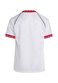 Bijela sportska dres s geometrijskom teksturom, crvenim detaljima na rukavima i izrezu, i crnim šavovima. Prikazano stražnje gledište.