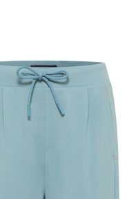 Svetlomodré jogger nohavice majú elastický pás s ktorým sa dá stiahnuť, dve bočné vrecká a jemné záhyby na prednej strane.