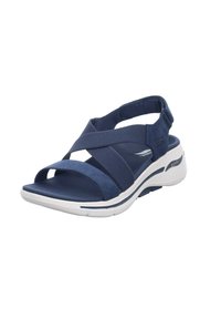 Sandalo blu con design a strappo incrociato, realizzato in tessuto texturizzato e gomma. Presenta una soletta imbottita e un accento di intersuola bianco.