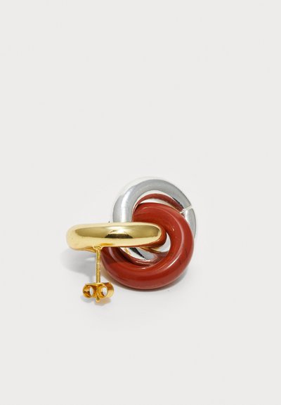 Boucle d'oreille en métal doré avec un design en tourbillon rouge et argenté tordu. Texture lisse avec une finition polie. Fermeture à épingle.