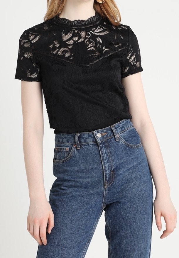Černý krajkový top s květinovým vzorem, krátkými rukávy a vroubkovaným výstřihem, v kombinaci s džíny s vysokým pasem.