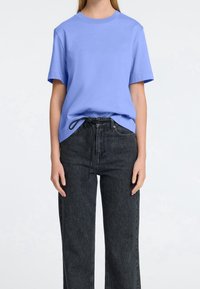 Jasnoniebieska bawełniana koszulka z krótkim rękawem i okrągłym dekoltem, zestawiona z czarnymi dżinsami o wysokim stanie z trokami.