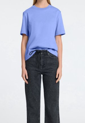 T-shirt en coton bleu clair à manches courtes et col rond, associé à un jean en denim noir taille haute avec cordon de serrage.