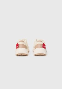 Sneakers con una toma superiore in rete crema, dettagli in tan e un'etichetta rossa sul tallone. Suola in gomma con grip testurizzato per una migliore aderenza.